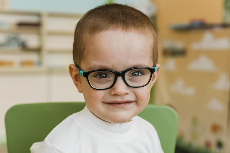 Little Boy playing while wearing glasses.